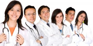 friendly young doctors smiling over a white background - focus is on the female doctor on the left